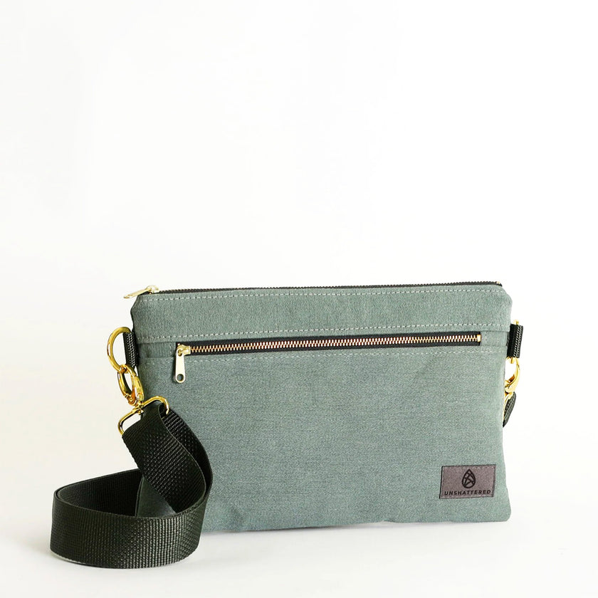 Green crossbody bag with a strap on a white background