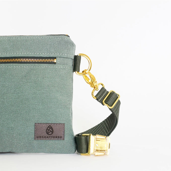 Green bag with a matching strap and gold hardware on a white background