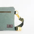 Green bag with a matching strap and gold hardware on a white background