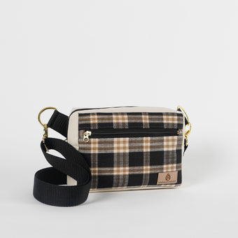 Plaid patterned crossbody bag with black strap on a light gray background