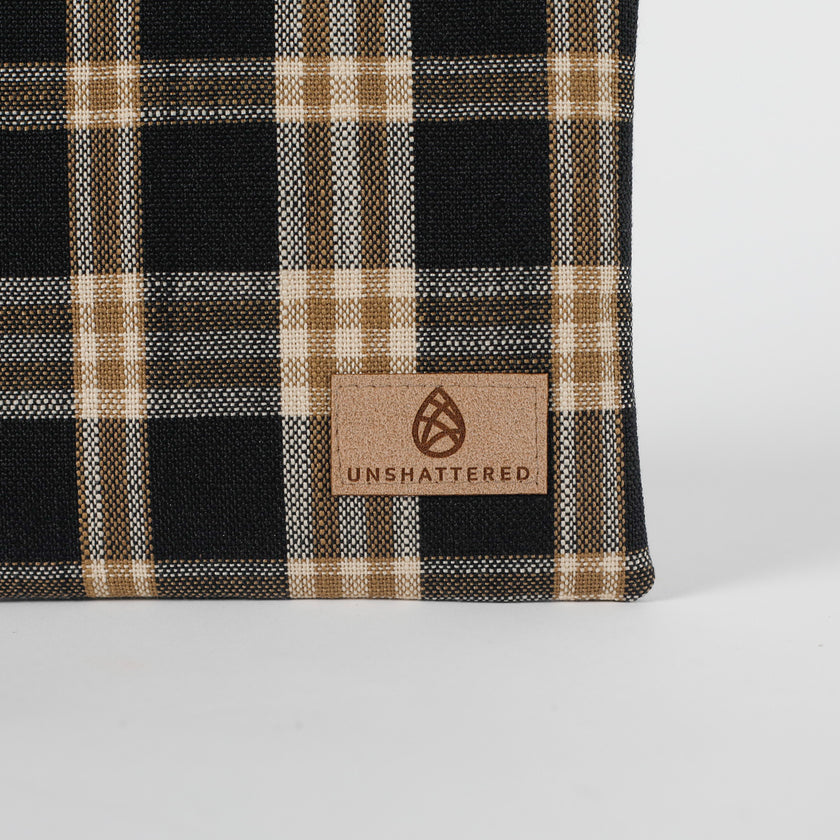 Plaid fabric with a 'Unshattered' brand label on a white background