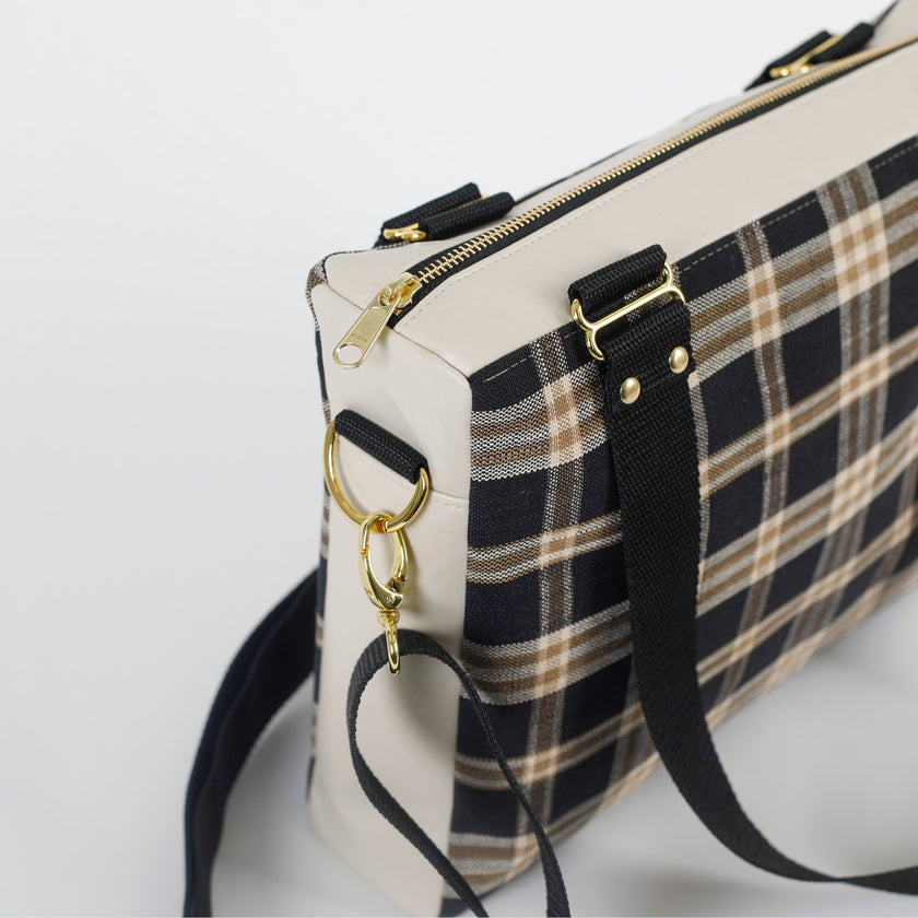 Handbag with plaid pattern and gold accents on a white background