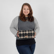 Woman holding a plaid bag against a plain background