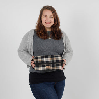 Woman holding a plaid bag against a plain background