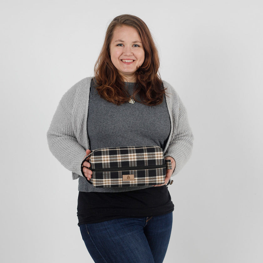 Woman holding a plaid bag against a plain background