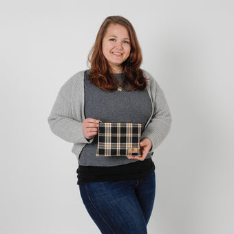 Woman holding a plaid pouch against a plain background