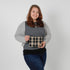 Woman holding a plaid pouch against a plain background