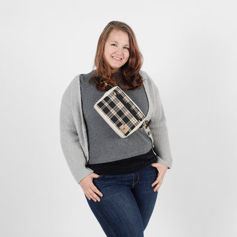 Woman wearing a gray sweater with a plaid bag over her shoulder on a white background