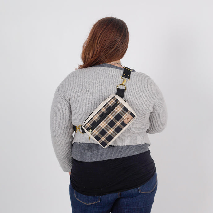 Person wearing a plaid crossbody bag on a plain background