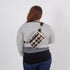 Person wearing a plaid crossbody bag on a plain background