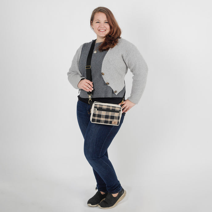 Woman wearing a plaid crossbody bag against a white background