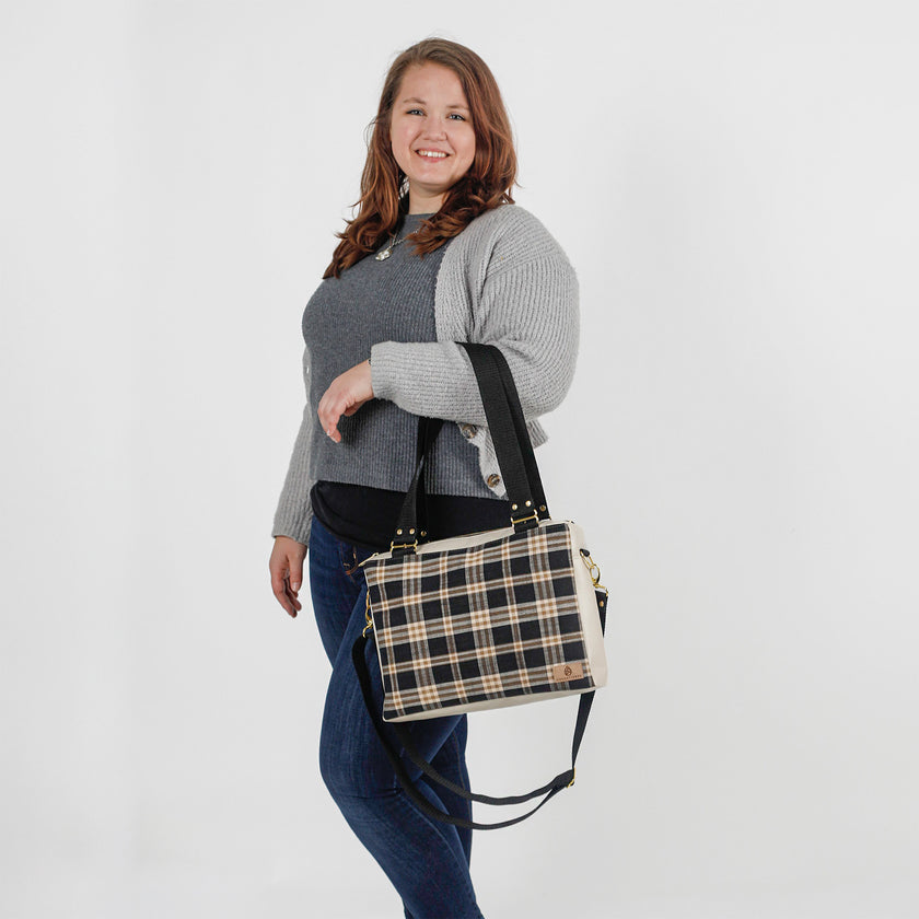 Woman holding a plaid bag against a white background