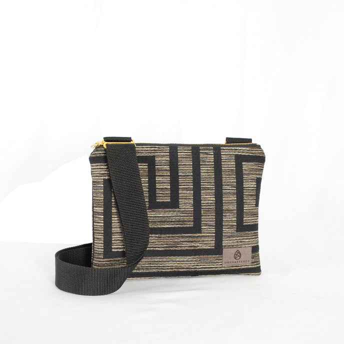 Crossbody pouch with geometric pattern and black strap on a white background