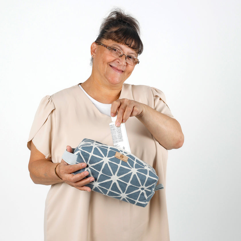 Woman holding a blue geometric-patterned pouch pulling something out of toiletry