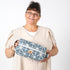 Woman holding a blue geometric-patterned bag against a white background