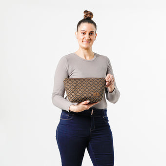 Woman holding a makeup bag with a brown and blue geometric pattern on a white background