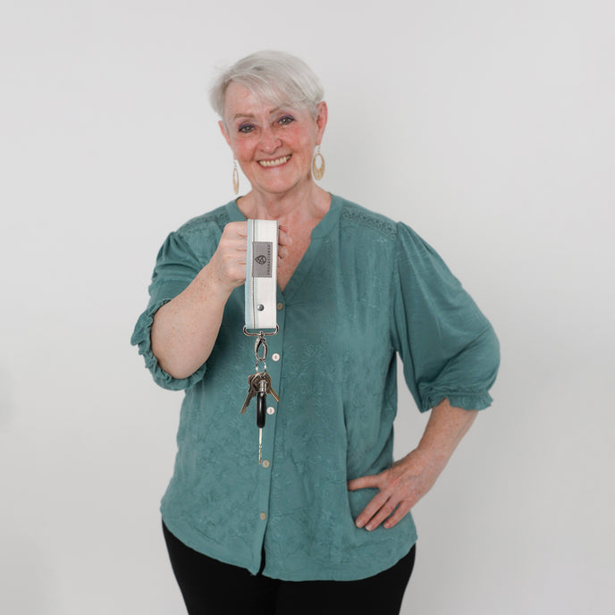 Woman holding a white and blue key clip against a white background