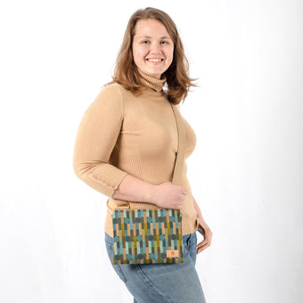 Woman holding a crossbody bag with geometric pattern and beige strap against a white background