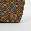 Close up of a brown, ultrasuede Unshattered label on a makeup bag with a brown and blue geometric pattern