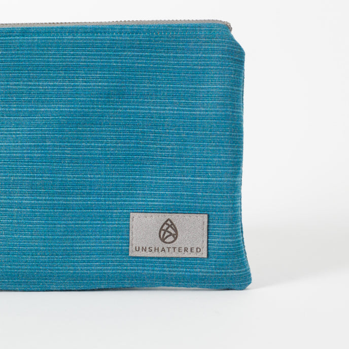 Blue textured pouch with 'Unshattered' brand logo on a white background