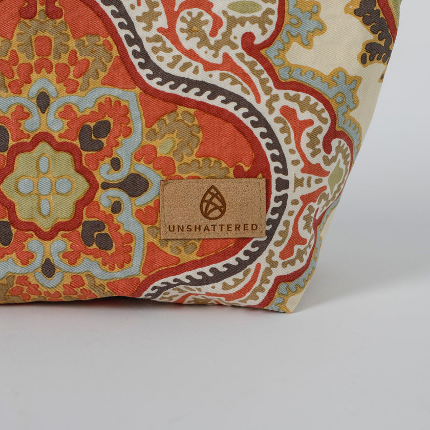 Decorative makeup bag wiith intricate pattern and 'Unshattered' brand label on a white background