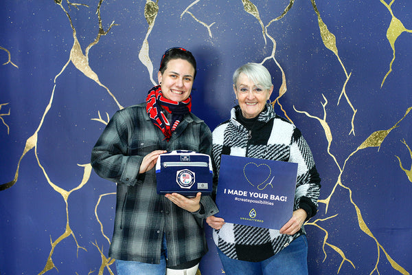 Two people holding 'I Made Your Bag' signs against a decorative blue and gold background