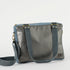 A charcoal  and blue convertible handbag with gold-tone hardware, an adjustable crossbody strap, and a floral patterned interior.