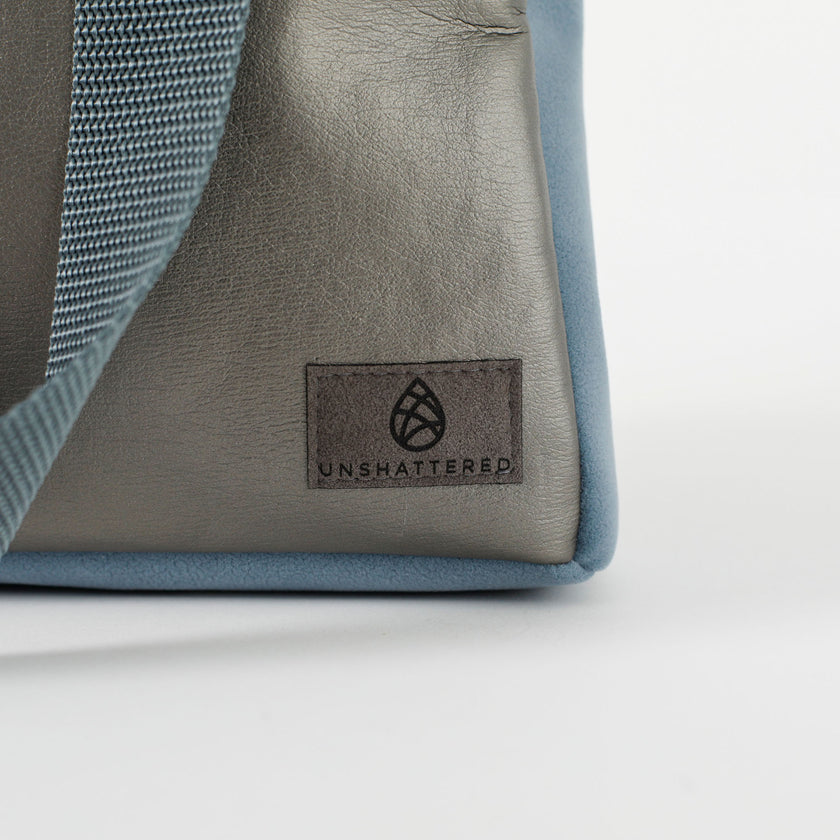 A gray label on a charcoal luxury leather alternative handbag with blue velvet accents