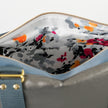 A white fabric with bright colorful flowers on the interior on a charcoal handbag with blue velvet accents 