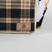 Plaid bag with 'Unshattered' brand logo on a white background