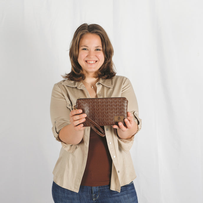 Woman holding a brown wristlet against a white background