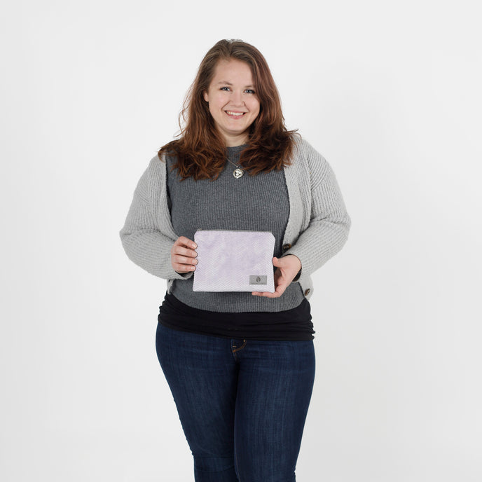 Woman holding a light purple zip pouch  against a white background