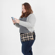 Woman wearing a plaid belt bag on a white background