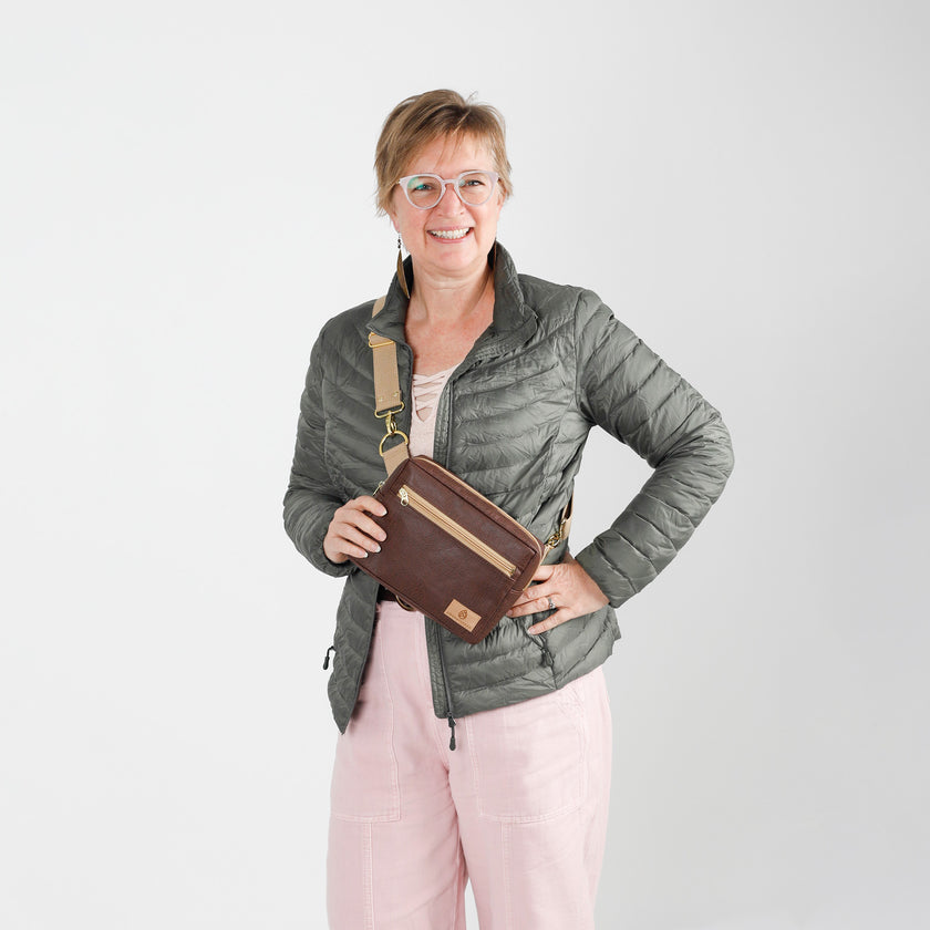Woman holding a brown vegan leather bag against a white background