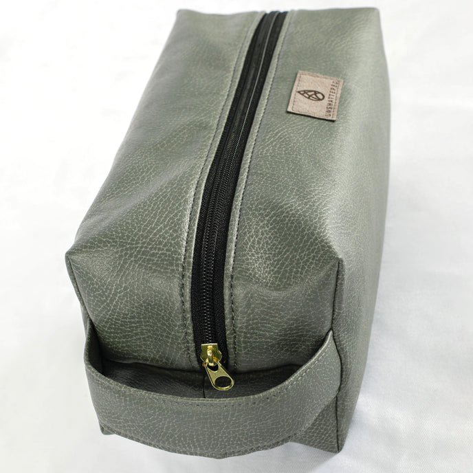 A gold tone zipper on a gray toiletry kit 