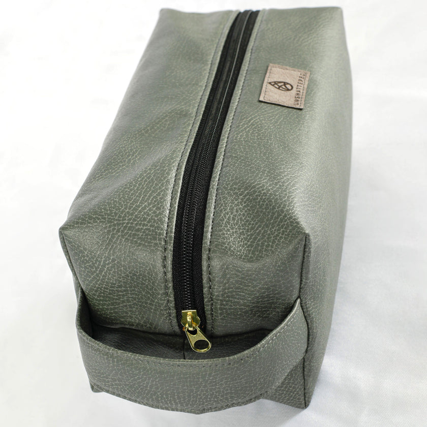 A gold tone zipper on a gray toiletry kit 