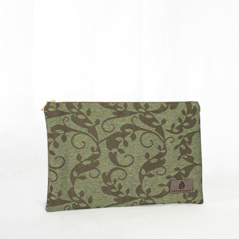 A green floral zip pouch with gold-tone hardware, closed and laid flat on a surface.