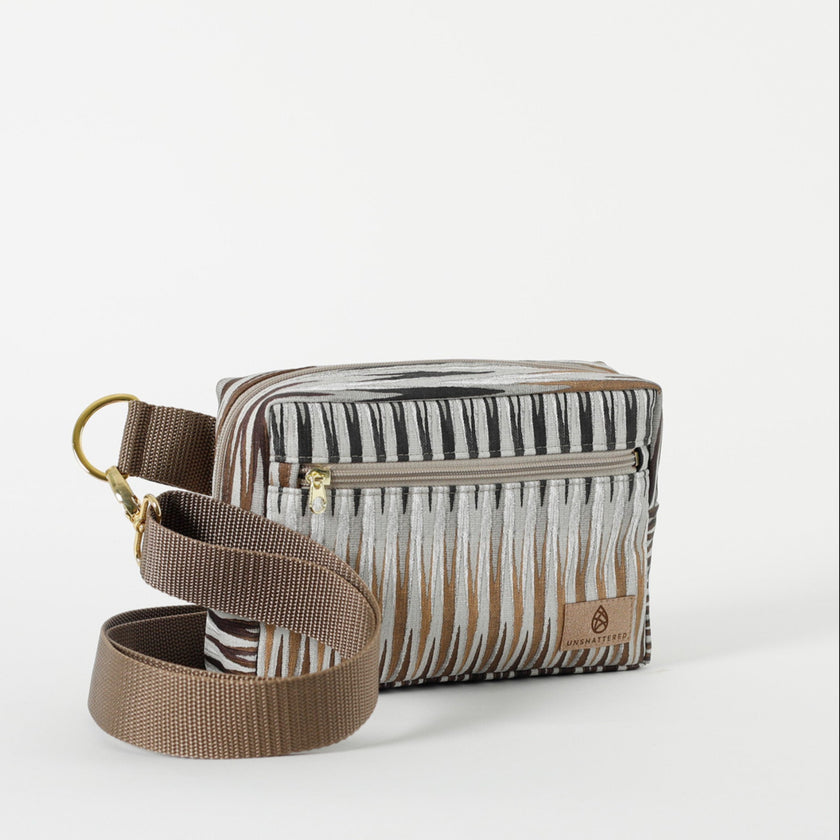 A handcrafted errand bag with a brown chevron pattern in muted colors with a front zip pocket and an adjustable strap named after Sally