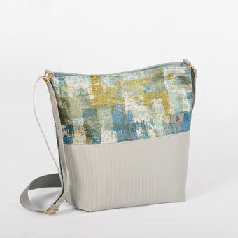 A multicolored tote handbag with a geometric pattern on the top half and a solid color on the bottom half, featuring a strap and gold-tone hardware