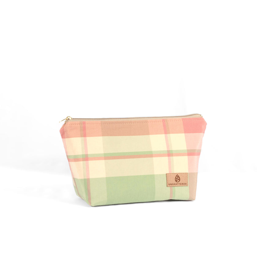 A pastel plaid makeup bag named Quela with a zip closure and gold-tone hardware on a white background