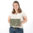 A woman holding a green and brown floral large zip pouch with a gray label  