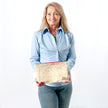 A woman holding a large zip pouch handcrafted from upcycled beige velvet fabric