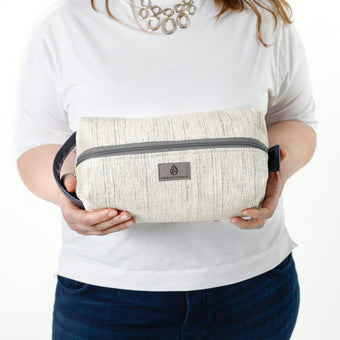 A woman holding a two toned twill weave toiletry kit with a gray label 