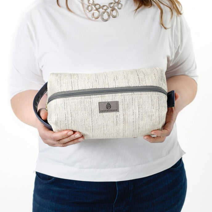 A woman holding a two toned twill weave toiletry kit with a gray label 