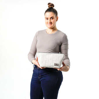 A woman holding a white two toned twill weave makeup kit made from upcycled material