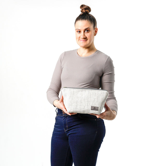 A woman holding a white two toned twill weave makeup kit made from upcycled material