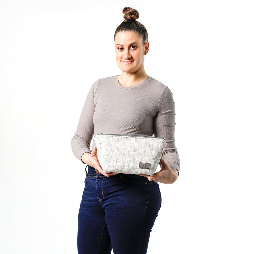 A woman holding a white two toned twill weave makeup kit made from upcycled material