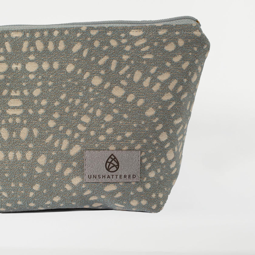 A gray label on a gray makeup bag with circles on a white background named after Abby