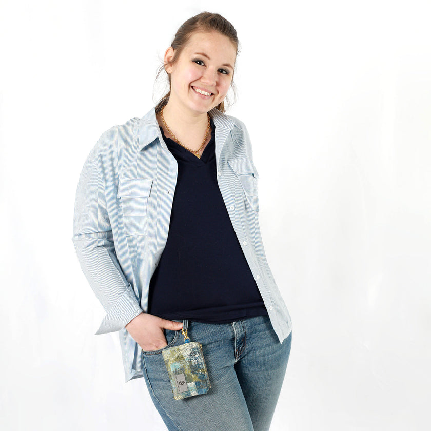 A woman with a small blue and green zippered pouch clipped to her jeans 