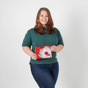 Person holding a red and white patterned pouch  against a white background named after Aiyannah 